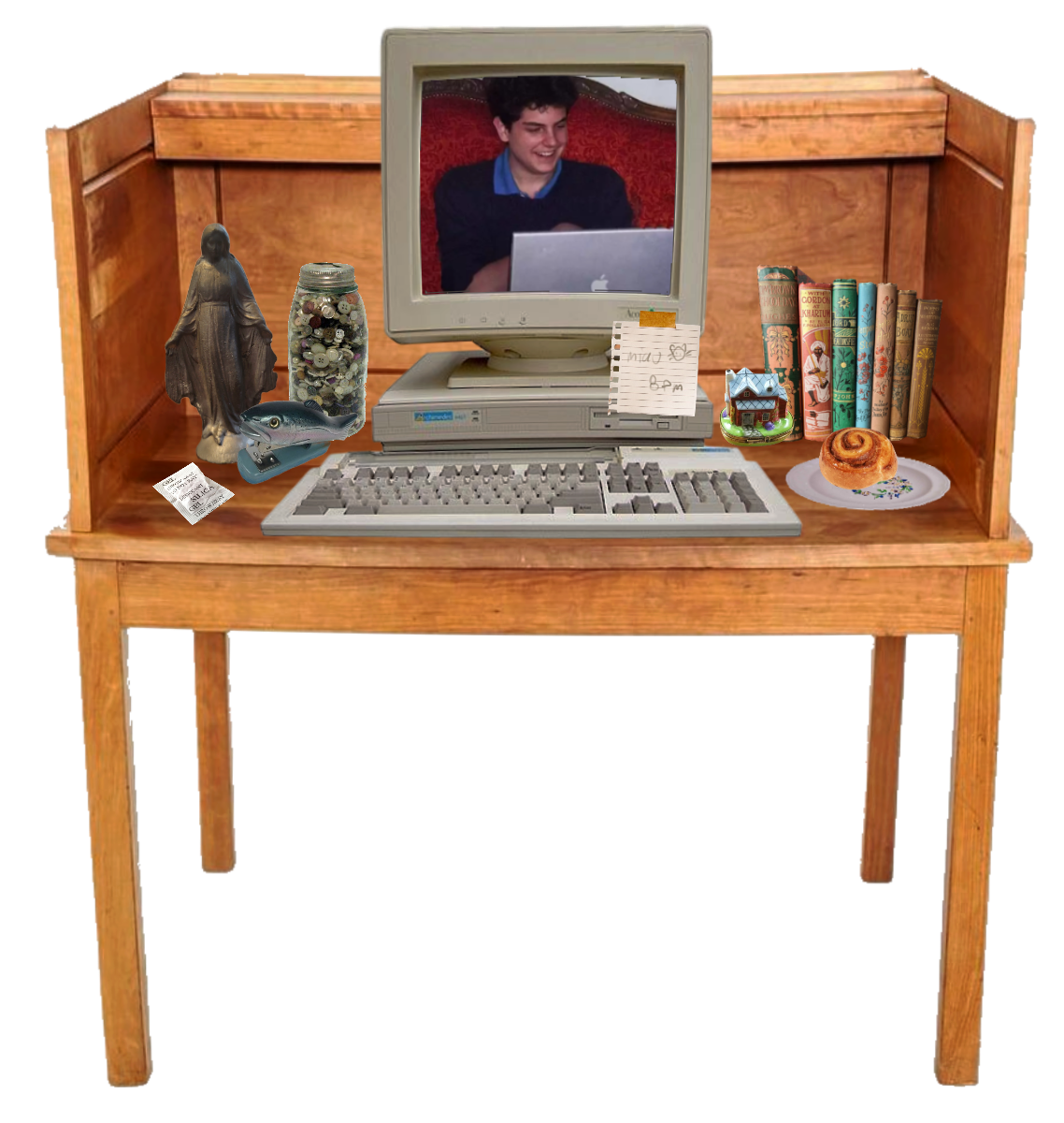 shrine to carlo acutis, depicted as a computer desk with books, a cinnamon roll in a plate, a Virgin Mary statue and a fish-shaped stapler. It has a desktop computer with a photo of Carlo Acutis in it
